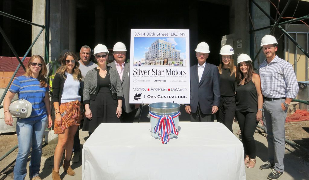 Shown are developer Silver Star Motors, architect MADGI, and builder 1 Oak Contracting celebrating the completion of the structural frame. Photo credit: Peter Wilk/Wilk Marketing Communications.