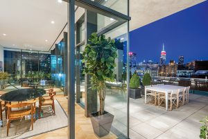 The glass-encased duplex at the top of the building houses a terrace, living space, and roof overhang that protects an art collection from sunlight. Photo credit: Tavros Development.